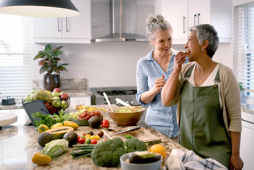 Two women in a kitchen with food on the counter.