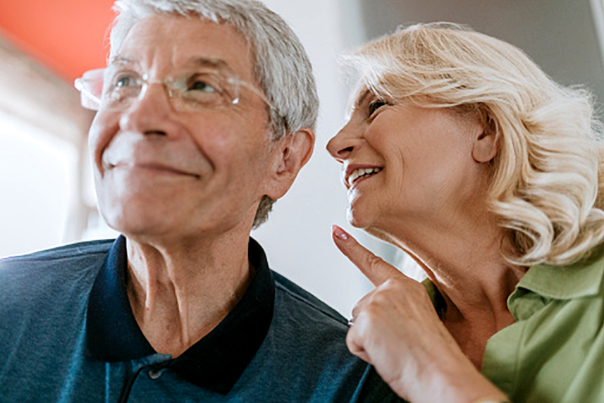 A woman pointing to a man's ear.