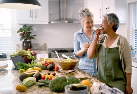 Two women in a kitchen with food on the counter.